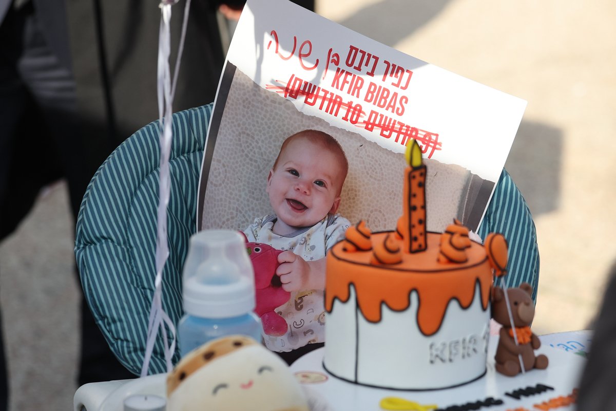 Детский стул с праздничным тортом рядом с фотографией Кфира Бибаса, во время акции в Тель-Авиве, 18 января 2024 года. Фото: Abir Sultan / EPA