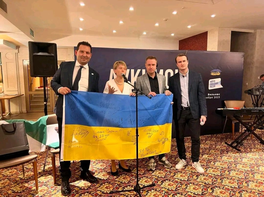 (слева направо) Иван Тютрин, Евгения Чирикова и Дмитрий Семенов держат флаг Украины с автографами бойцов ВСУ. Фото: forumfreerussia.org